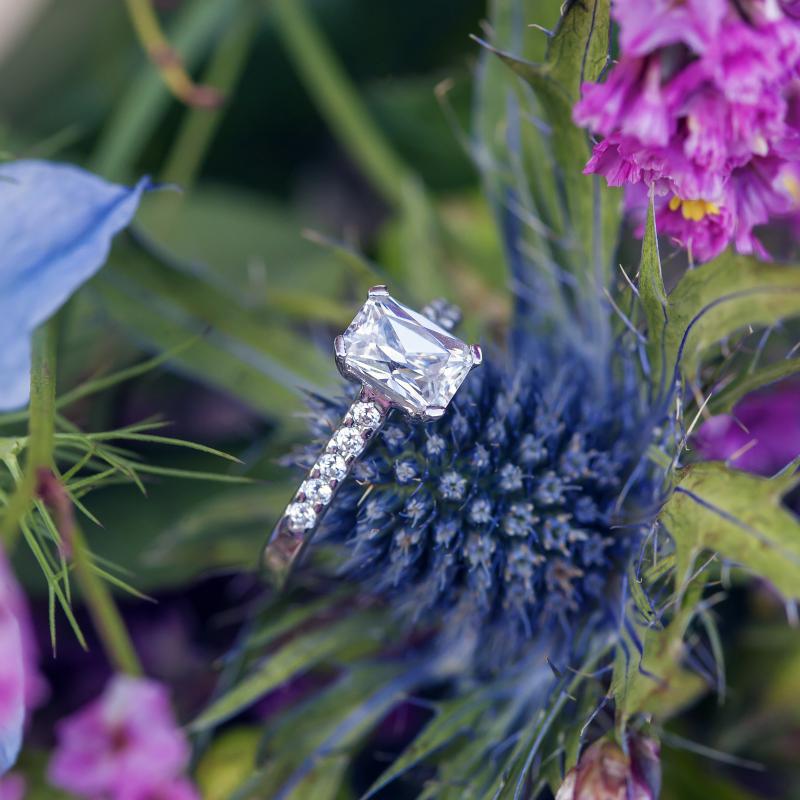 Ring mit Diamanten in Smaragd-Schliff auf dem blumen Hintergrund 12204