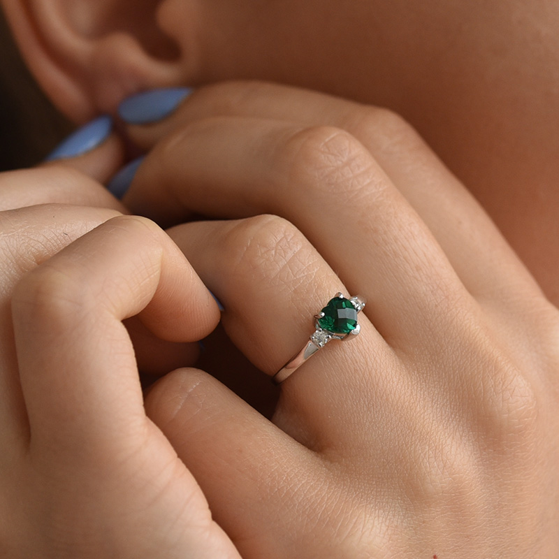 Herz in Smaragd im Ring mit Diamanten auf dem Finger