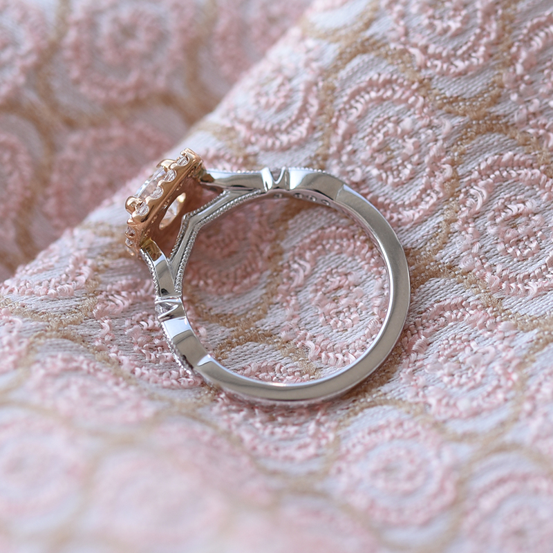 Ring mit Diamanten im Halo-Stil auf dem rosa Hintergrund