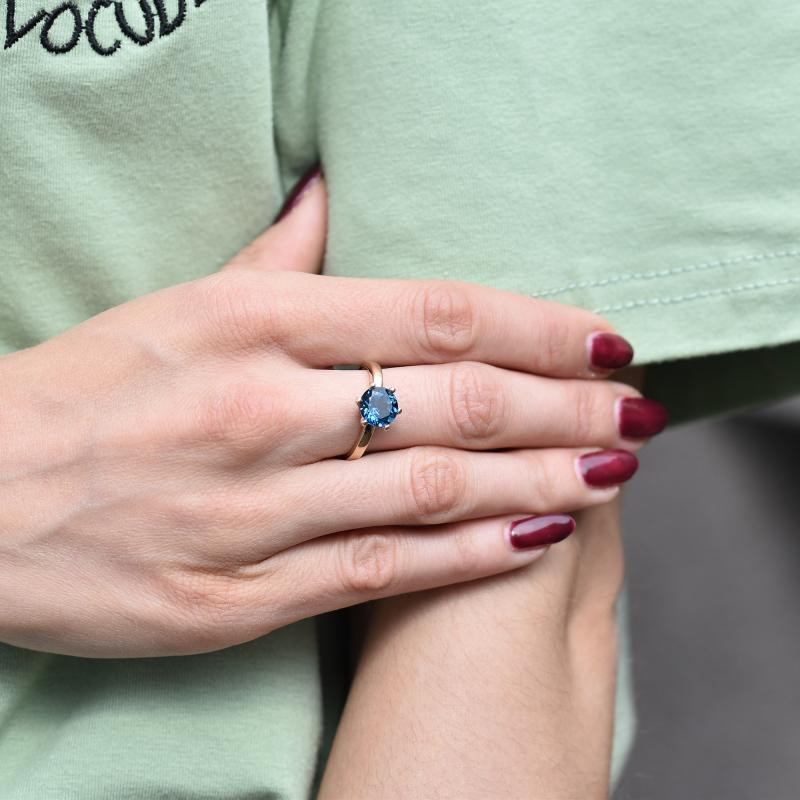 Goldener Verlobungsring mit blauem Topas auf dem Finger 30569