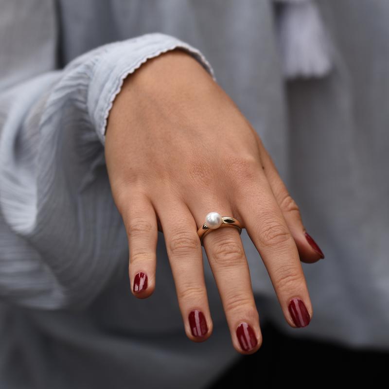 Goldener Verlobungsring mit weißer Perle auf dem Hand 48259